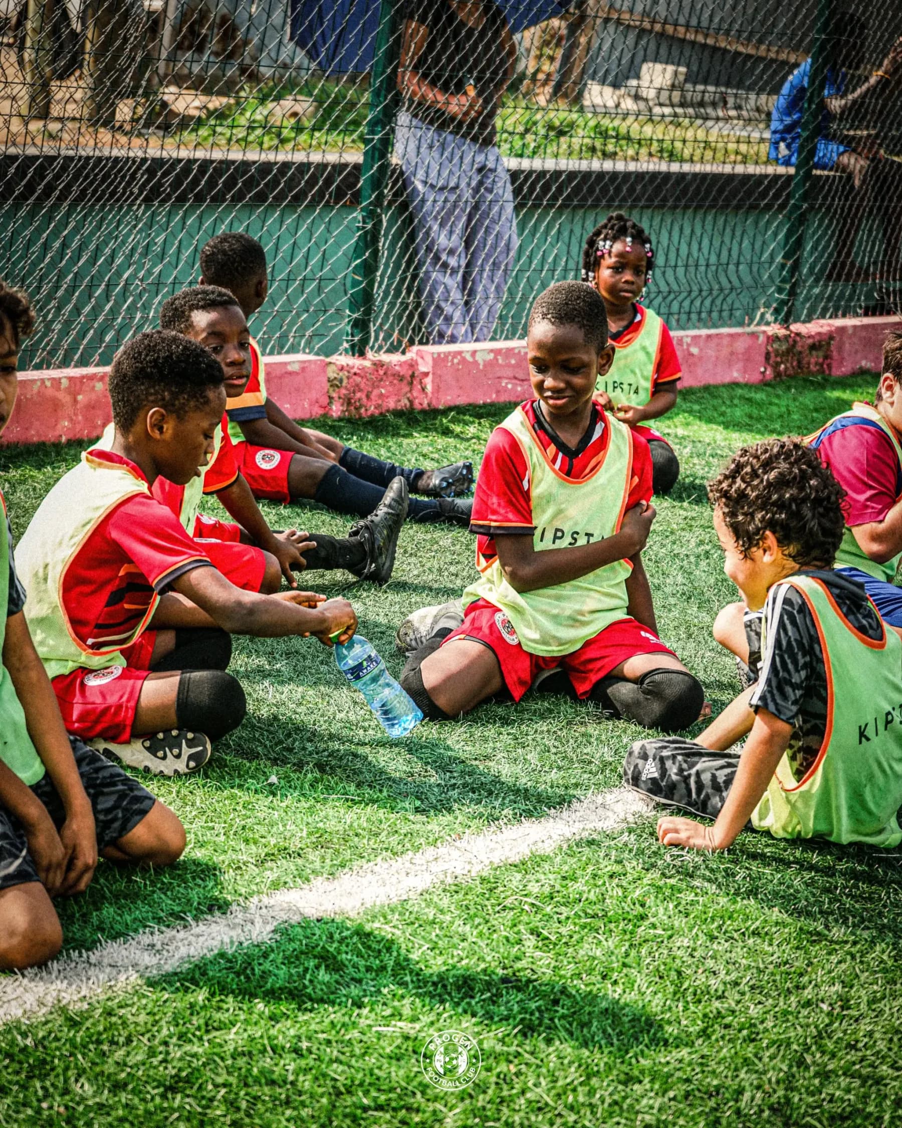 Young players in training bibs sitting on the pitch